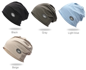 Detail view of four knitted beanies in black gray blue and beige with logo patch