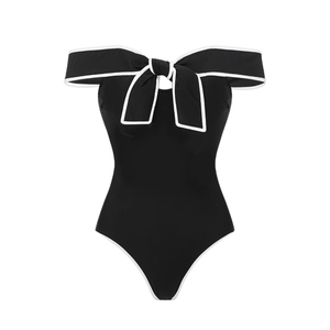 Detail of elegant black one-piece swimsuit featuring white bow shoulder and contrast trim