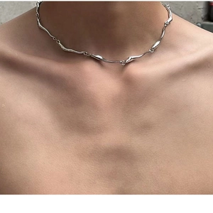 Close-up of irregular silver wave chain necklace worn on model's neck for detail