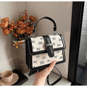 Elegante borsa a mano squadrata bianca e nera con stampa a fiocchi e dettagli in metallo