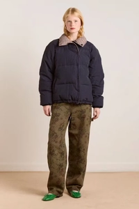 Front full view of woman in oversized navy blue puffer jacket with hem drawstring detail