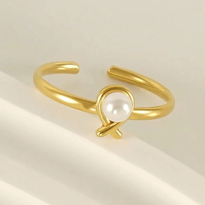 Adjustable gold plated stainless steel open ring with a pearl knot design on white blocks