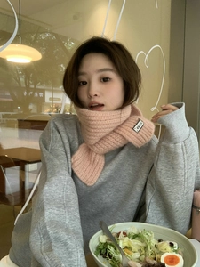 Detail of pink knitted scarf featuring a KN. STU woven label in a soft casual setting