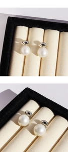 Close-up of elegant white pearl stud earrings with polished silver metal setting