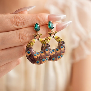 Detailed close-up of vintage peacock earrings with green teardrop gemstones and enamel