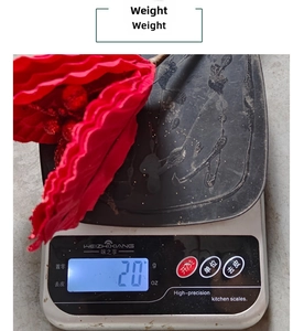 Detail view of a 20g lightweight red sequin Christmas flower on a digital scale
