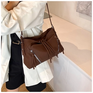 Dettaglio borsa moto in pelle marrone scuro con cerniera a frange sulla spalla modella