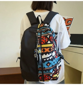 Rear view of model wearing a black backpack with colorful geometric ethnic patterns