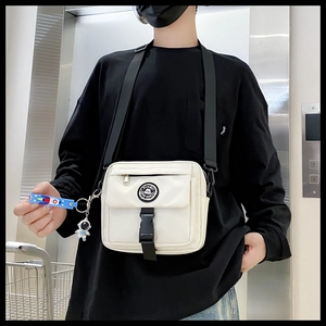 Close-up of a white techwear crossbody bag with astronaut keychain and Pinbo logo patch