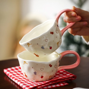 Close-up of cute ceramic mug with cartoon girl and rabbit patterns on red checkered cloth