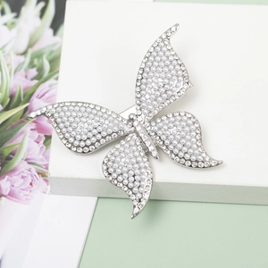 Sparkling butterfly hair clip with white pearls and rhinestones on a white stand