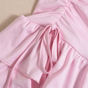 Detailed close-up of pink ruched fabric with drawstring ties and ruffle hem details