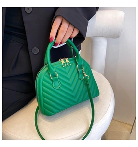 Green shell bag featuring V-shaped quilting and gold zippers shown on a model