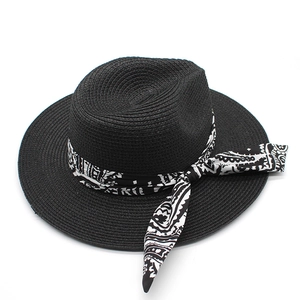 Close-up of black straw Panama hat featuring a black and white paisley silk ribbon bow