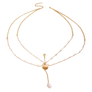 Detail of gold body chain featuring pink pearls and a baroque pearl seashell pendant