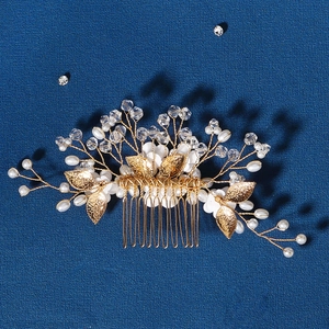 Exquisite bridal hair comb with gold leaves pearls and crystal flowers on navy backdrop