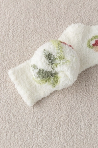 Close-up of soft beige coral fleece winter socks with green floral jacquard patterns