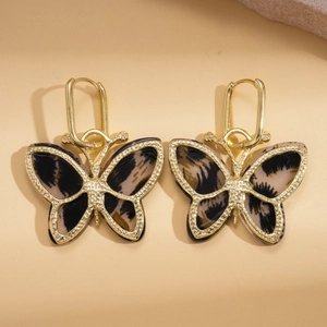 Elegant gold butterfly earrings with leopard print acetate inlay on beige leather background
