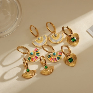 Détail de boucles d'oreilles plaquées or 18k avec émail et pierres vertes sur fond beige