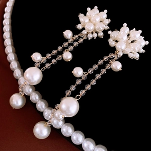 Détail de boucles d'oreilles fleur et collier en perles avec glands dorés sur fond noir