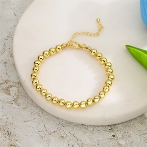 Detail of adjustable gold pearl bead bracelet on marble tray with elegant minimalist design