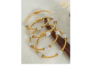 Detail of 18K gold plated spiral bangles with micro-pave zircon cylinders on wood