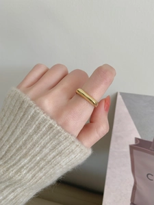 Minimalist polished wide irregular gold ring worn by model with beige knit cuff