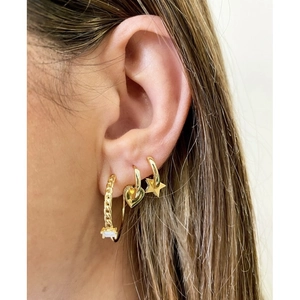 Detail of three gold earrings featuring star, heart, and zircon charms worn by a model