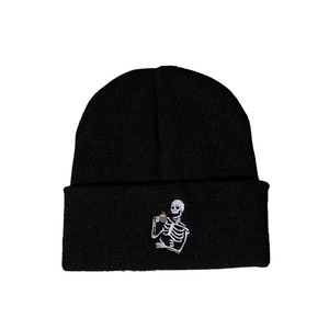 Bonnet en tricot noir avec broderie squelette blanc buvant du thé sur le bord replié