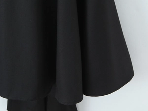 Close-up of matte black dress hem showing high-quality woven fabric and elegant drape