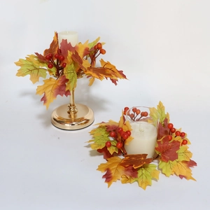 Detail of harvest candle holder with faux maple leaves, red berries and gold metal base