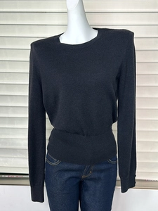 Detailed view of black knitted wool sweater with ribbed waist and decorative buttons