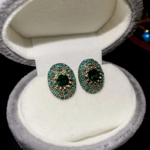 Macro shot of oval vintage studs with green center stone and surrounding crystals