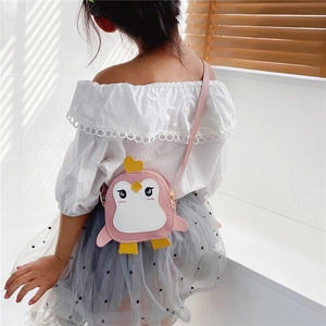 Detail view of pink penguin crossbody bag with 3D wings and heart decor on a child