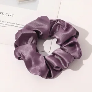 Close-up of a premium purple silk satin scrunchie with soft folds and elegant glossy finish