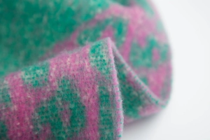 Macro shot of pink and teal bouclé fabric texture with soft wool-like curly fringe