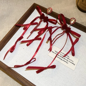 Détail de boucles d'oreilles nœud rouge avec perles et longues franges en strass