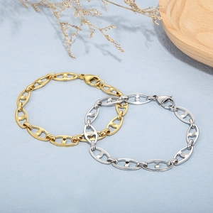 Polished gold and silver stainless steel oval anchor link bracelets on a wooden tray