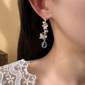 Detailed shot of gold butterfly earrings with blue teardrop stones and zircon accents