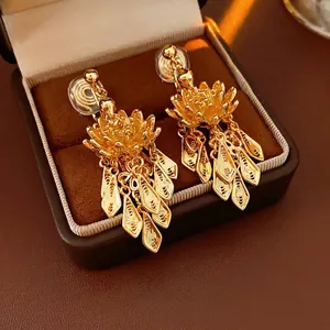 Gold-plated lotus flower tassel clip-on earrings with textured leaf pendants in a jewelry box