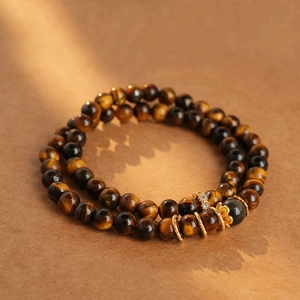 Detail of tiger eye stone bracelet with golden flower charms and sparkling zircon beads