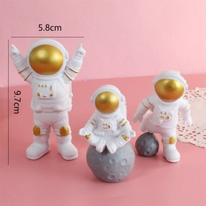 Three gold-masked astronaut cake toppers in resin, including a moon-seated pose, 9.7cm high