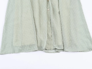 Détail de robe en mousseline vert clair à pois avec boutons décoratifs devant