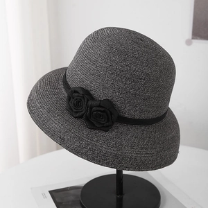 Détail d'un chapeau cloche en paille gris foncé avec ruban noir et roses en tissu