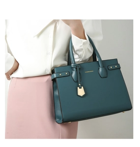 Detail of dark green PU leather handbag featuring lychee texture and gold metal hardware