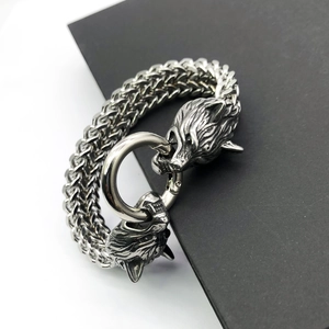 Macro detail of Nordic wolf head connectors and woven stainless steel chain on men's bracelet