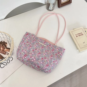 Détail du sac fourre-tout fleuri en toile avec anses roses et étiquette sur table