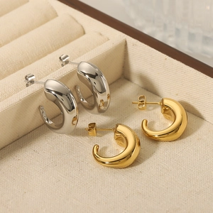Polished C-shape thick hoop earrings in gold and silver finish on a jewelry tray