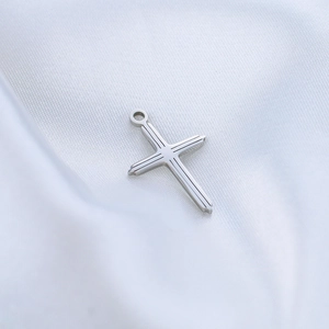 Polished silver stainless steel cross pendant with linear engraving on white silk background