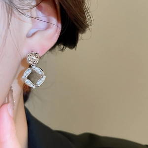 Detail view of square pearl drop earrings with 18K gold plating on a female model